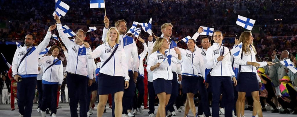 Suomen olympiamaajoukkue heiluttaa Suomenlippuja
